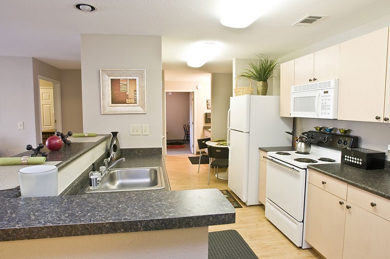 Model kitchen with white appliances and double stainless-steel sink